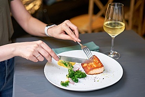 a woman eating salmon at a restaurant that is covered by spoilage and liability insurance