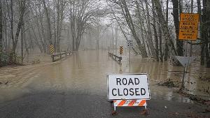Road closed warning sign on the edge of a flooded street