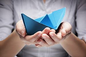 Boat insurance agent holding paper boat