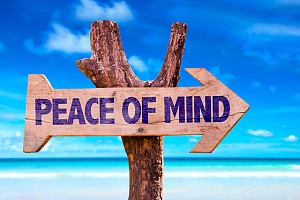 the words peace of mind on a large wooden stick sign on a beach