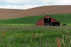 barn with a car that is covered by farm and ranch insurance