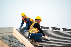 construction worker with construction insurance using nail gun to install new roof