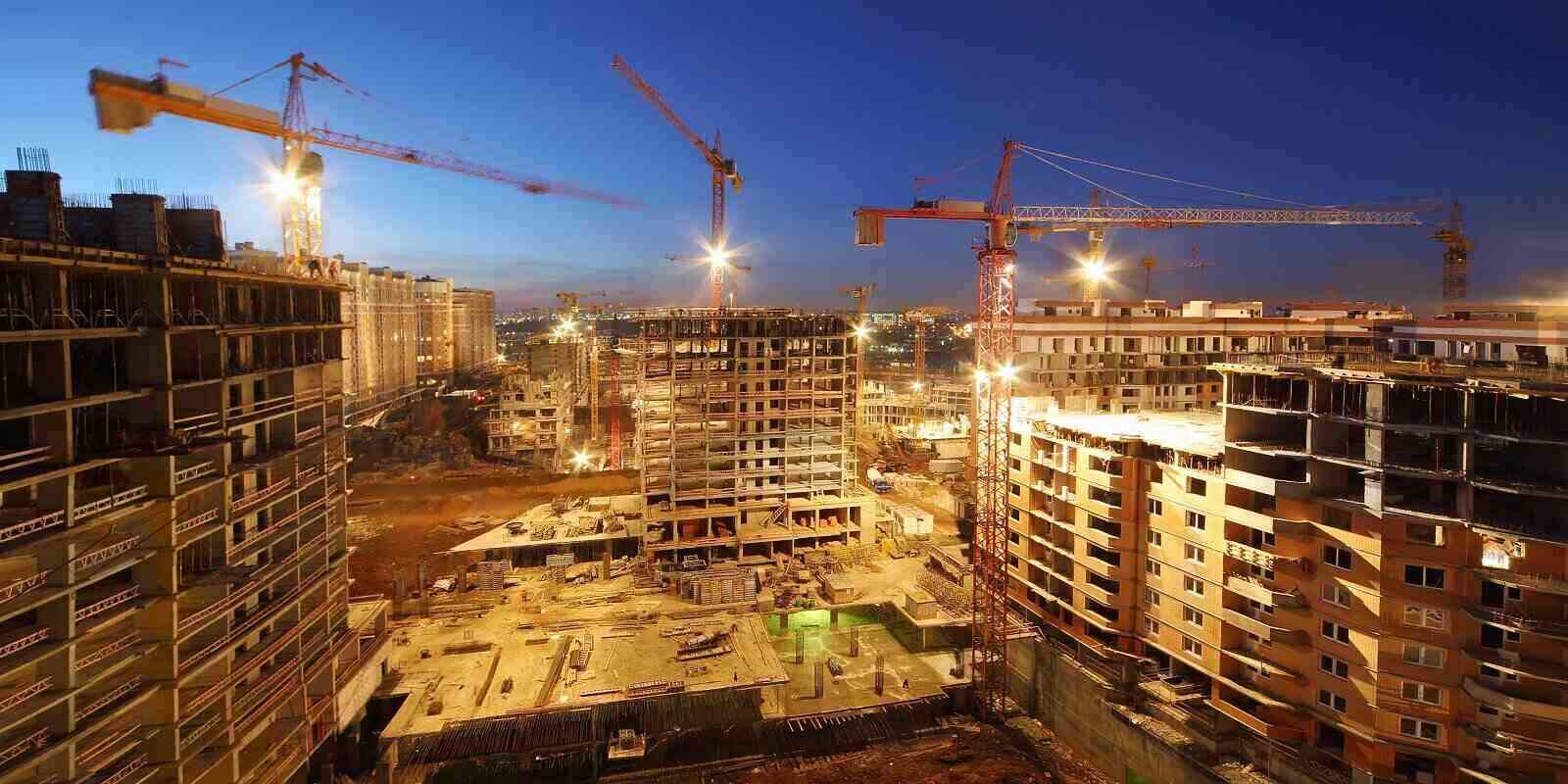 lots of tower cranes build large residential buildings at night