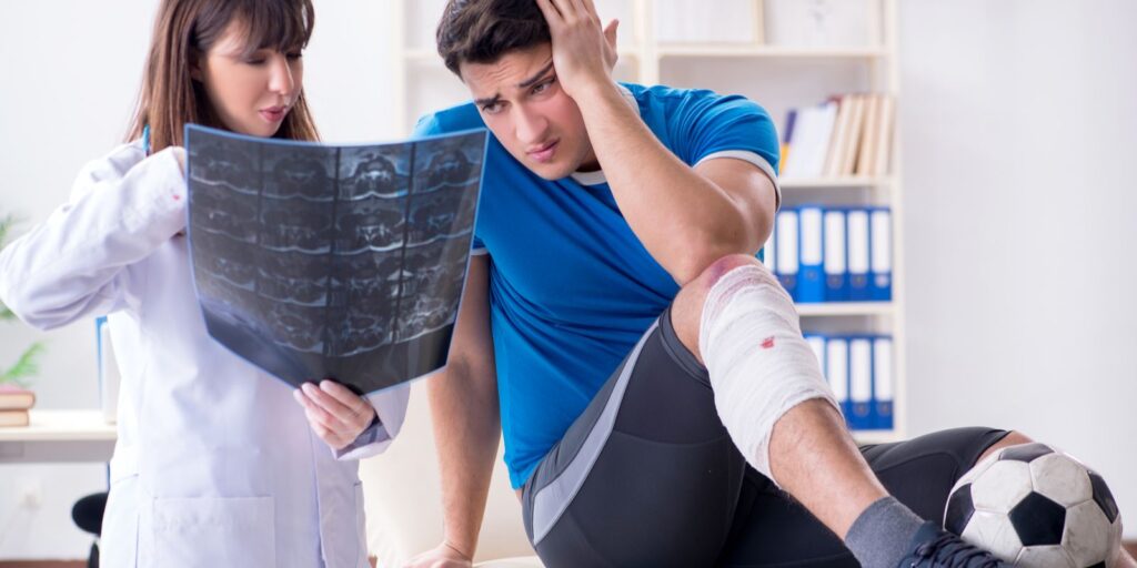 An sports insured football player consulting his doctor about leg injury