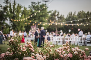wedding ceremony with flowers outside in the garden with hanging lights