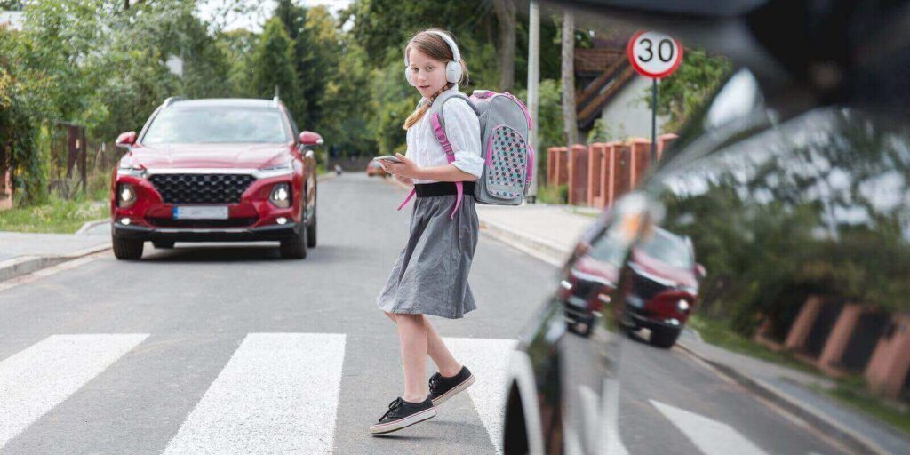 scared girl with phone and headphones runs away from the car at a pedestrian crossing