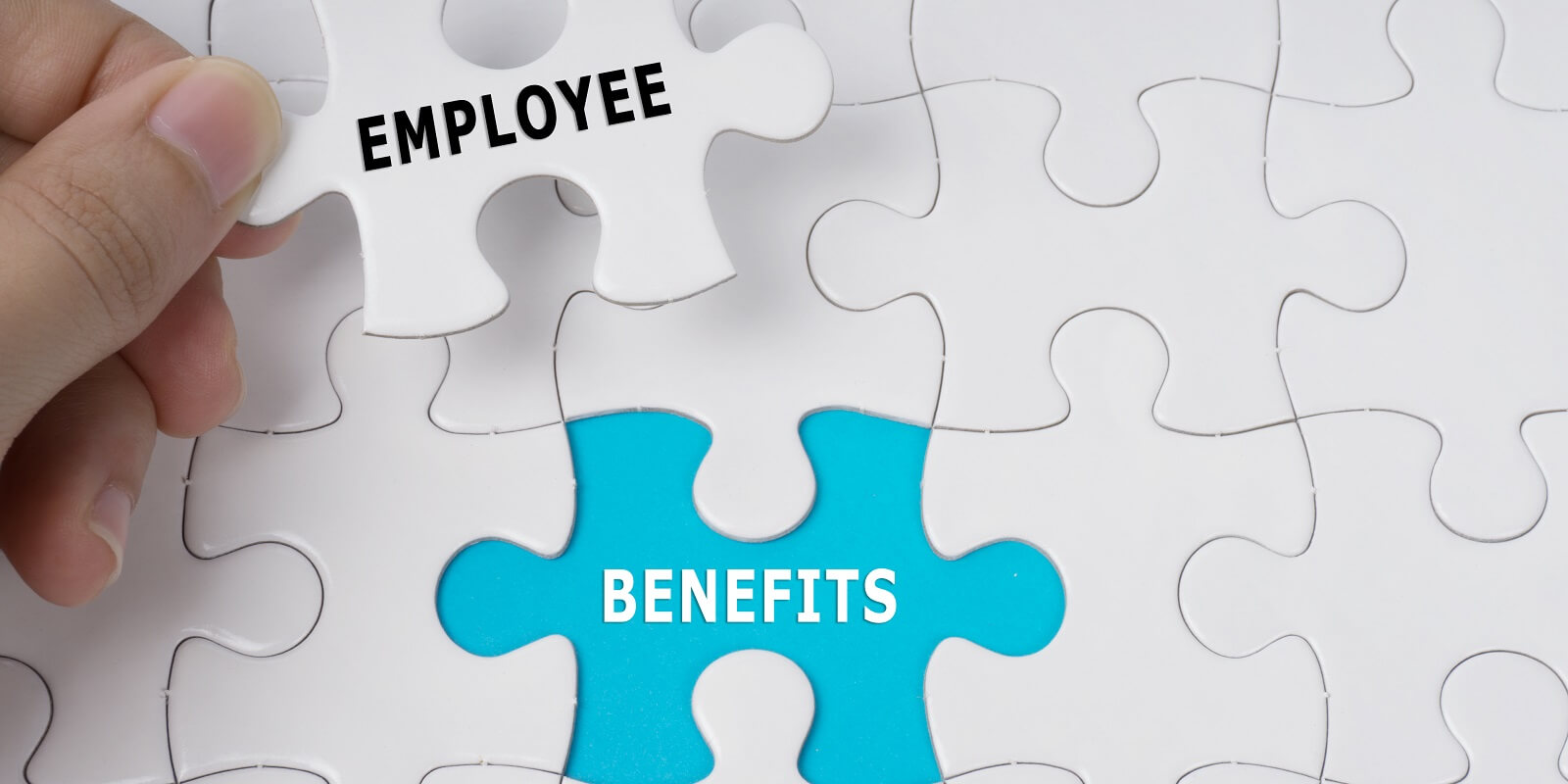 hand holding piece of jigsaw puzzle with words employee benefits