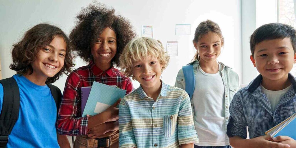 junior school students children group looking at camera standing in classroom