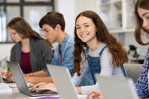 smiling school student working on laptop