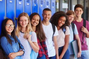 Teenage school kids smiling to camera in school corridor