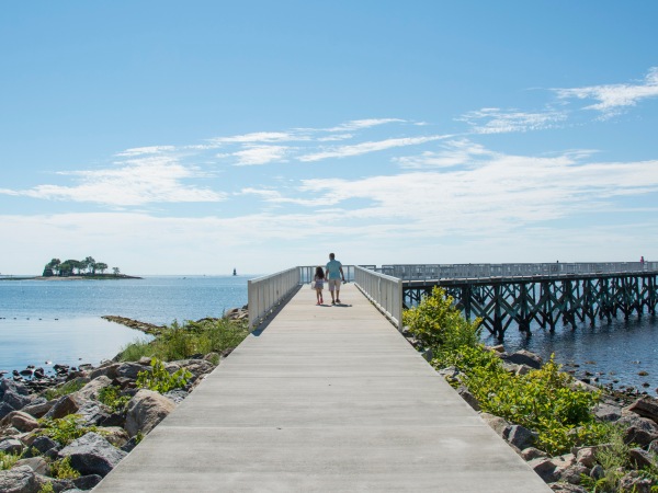 A view down the pier boardwalk on a beautiful summer day by the Long Island Sound at Calf Pasture Beach in Norwalk, Connecticut USA
