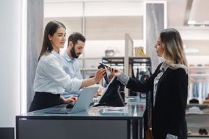 young woman at counter buys clothes from friendly retail sales assistant