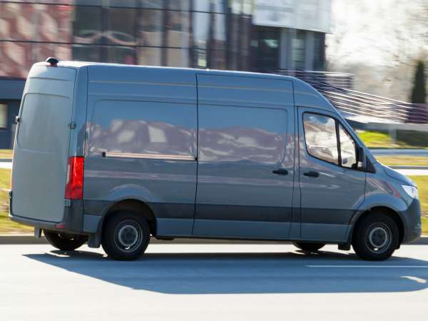 A gray van drives down the street. A moving cargo minibus. Cargo transportation, commercial transport. Motion blur.
