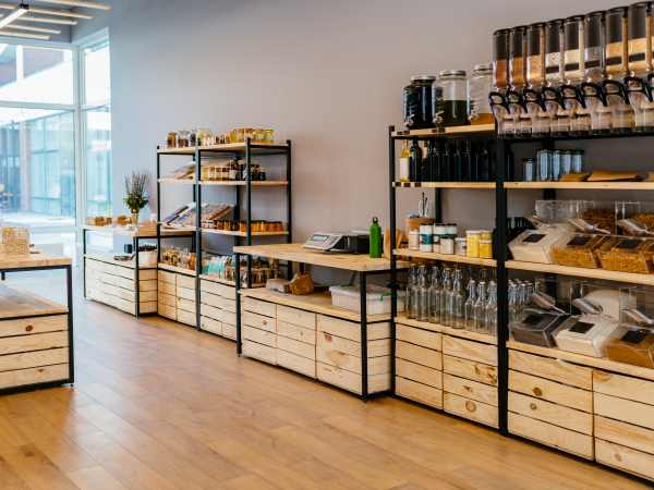 Zero waste shop interior details. Wooden shelves with different food goods and personal hygiene or cosmetics products in plastic free grocery store. Eco-friendly shopping at local small businesses.
