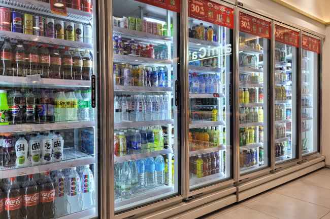 A variety of bottled and canned beverages displayed in glass-door refrigerators at FamilyMart. The selection includes soft drinks, juices and energy drinks