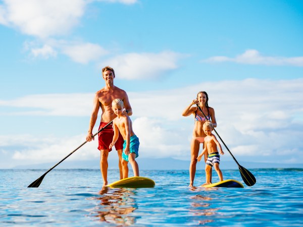 Family Having Fun Stand Up Paddling Together in the Ocean on Beautiful Sunny Morning