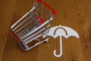 Shopping Cart and Umbrella on Wooden Table Showing Retail Insurance Concept