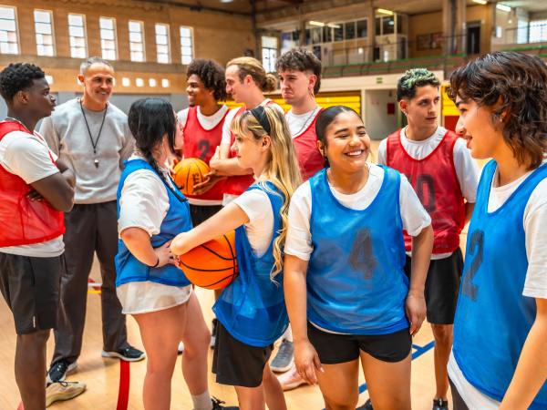 High school basketball team listening to their coach's instructions during a training session in the gym