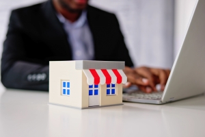 Man Working on Laptop Near Online Retail Store Model