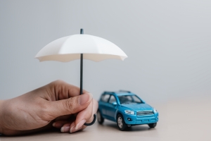 Hand with White Umbrella Protecting A Car Insurance Concept