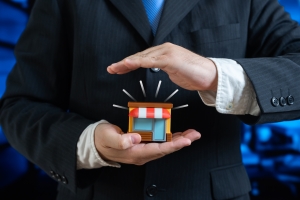 Hand Holding Small Shop Showing Retail Insurance Concept