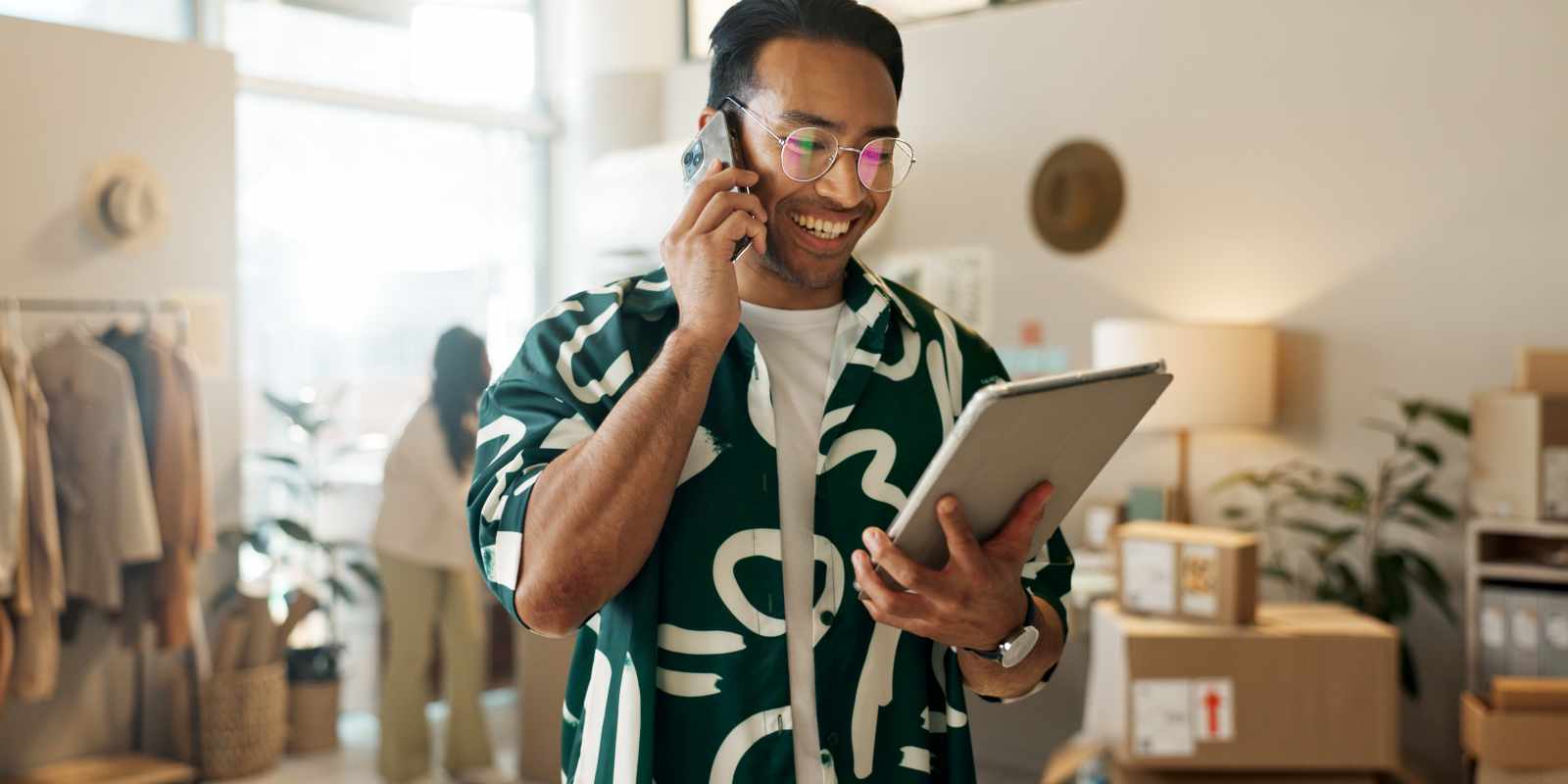 Retail Shop Owner Checking Insurance on Tablet While Talking Over Phone