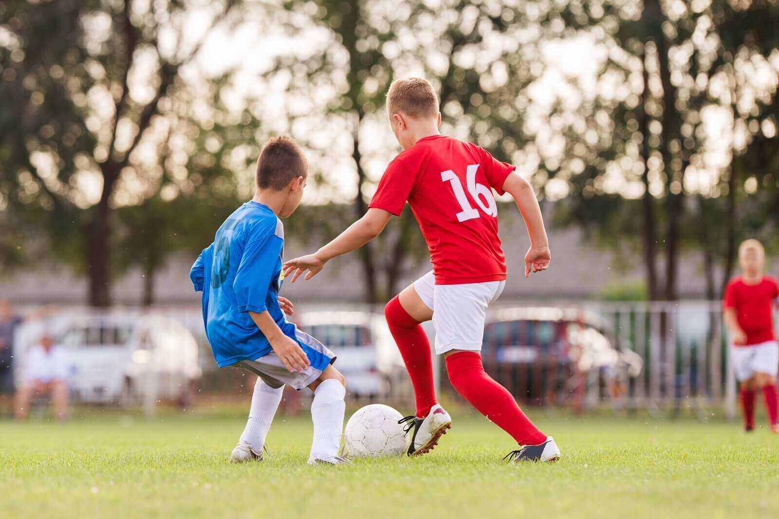 boys playing football soccer game on sports field