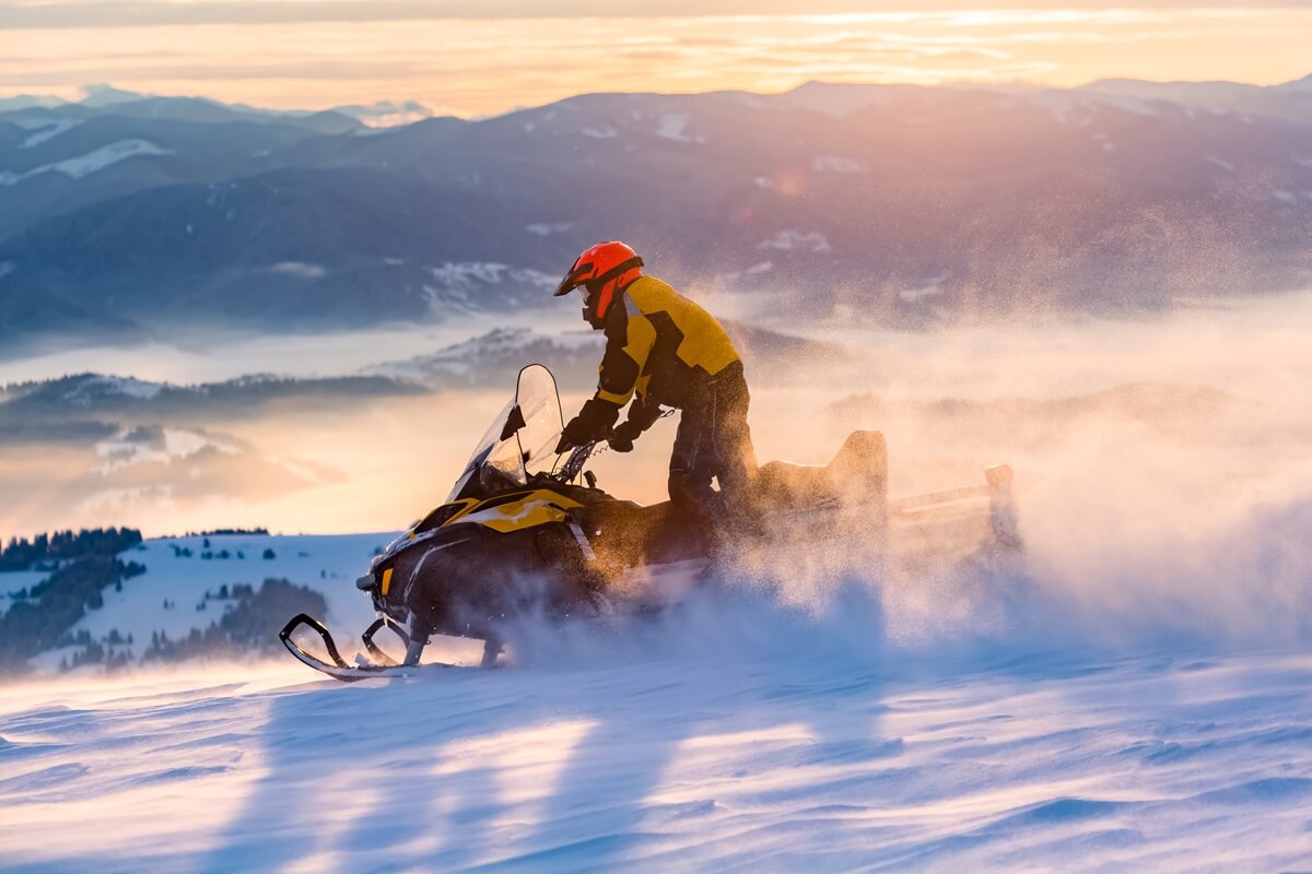 man is ridind snowmobile in mountains