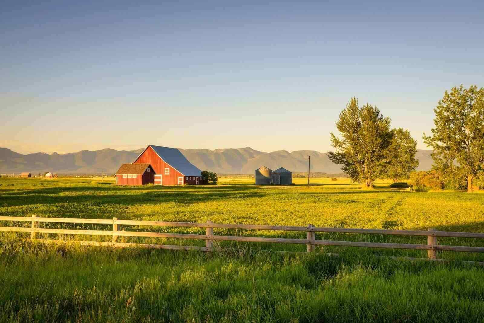 summer sunset with a red barn in rural montana and rocky mountains