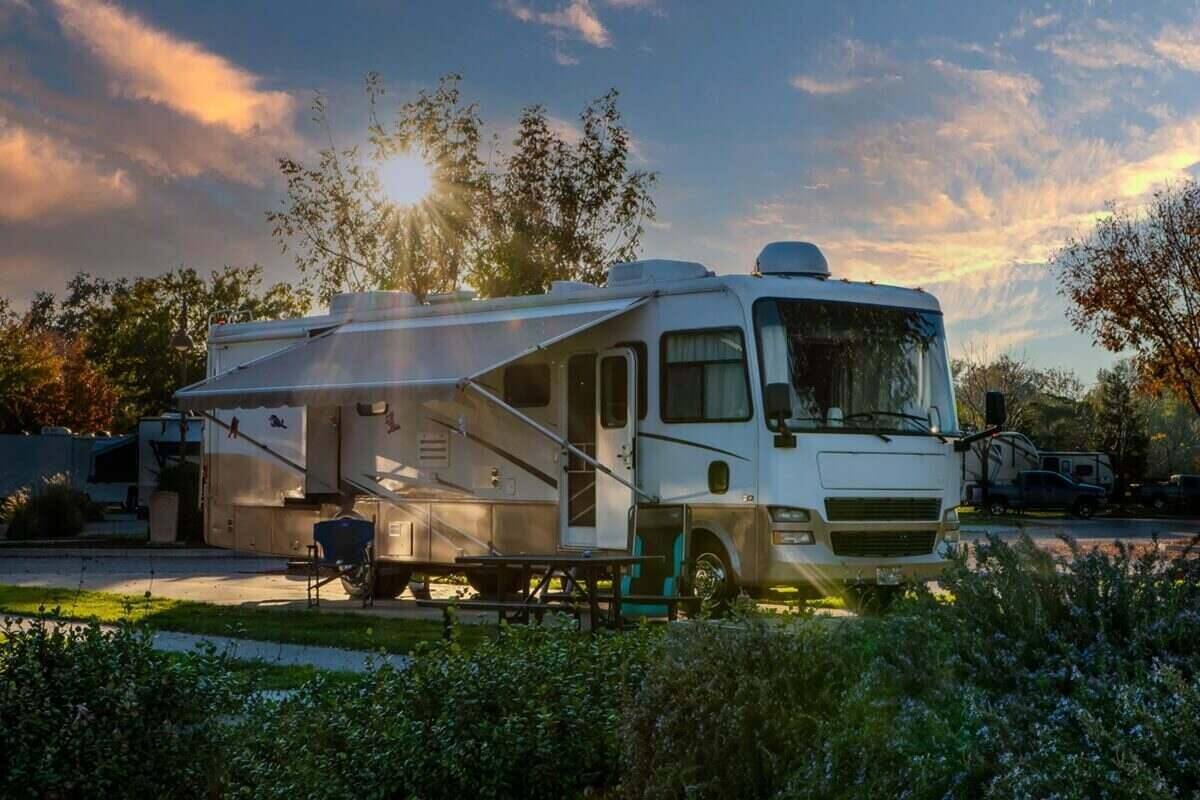 sunburst through the tree above a Rv parked at a campsite