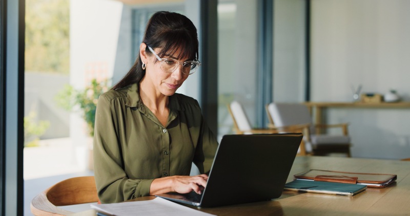 Business, woman and typing with laptop at house for real estate, property report and research. Mature freelancer, pc and paperwork for sales agreement, listing information and negotiation statement.