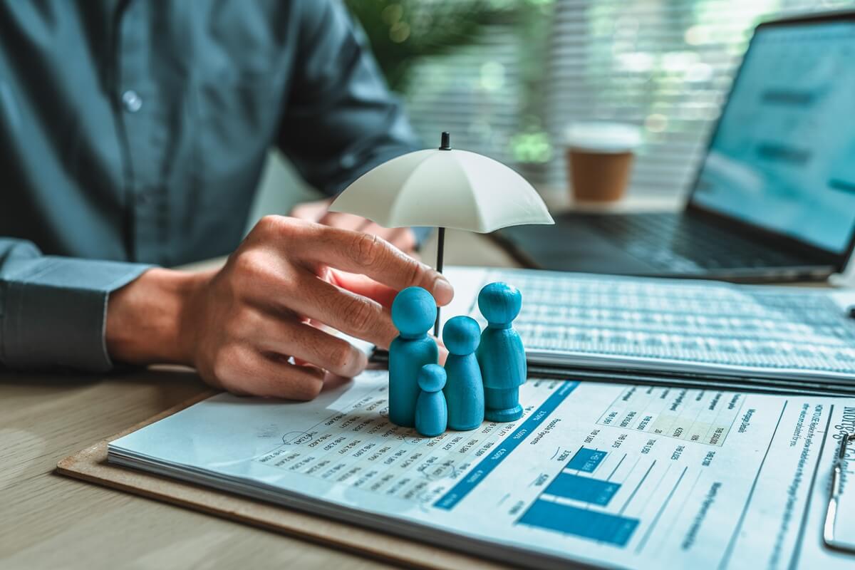 wooden doll under an umbrella holding by agent represent insurance