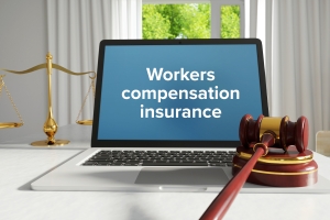 Workers Compensation Insurance Law Concept Through Text on Laptop and Judge Gavel