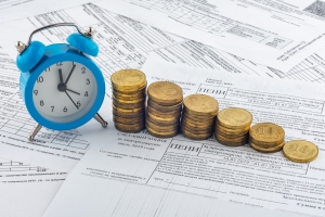 Increasing Coin Stacks Near Clock Representing Daily Fine Increase Concept
