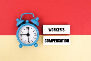 Wooden Blocks with Workers Compensation Text Near an Alarm Clock