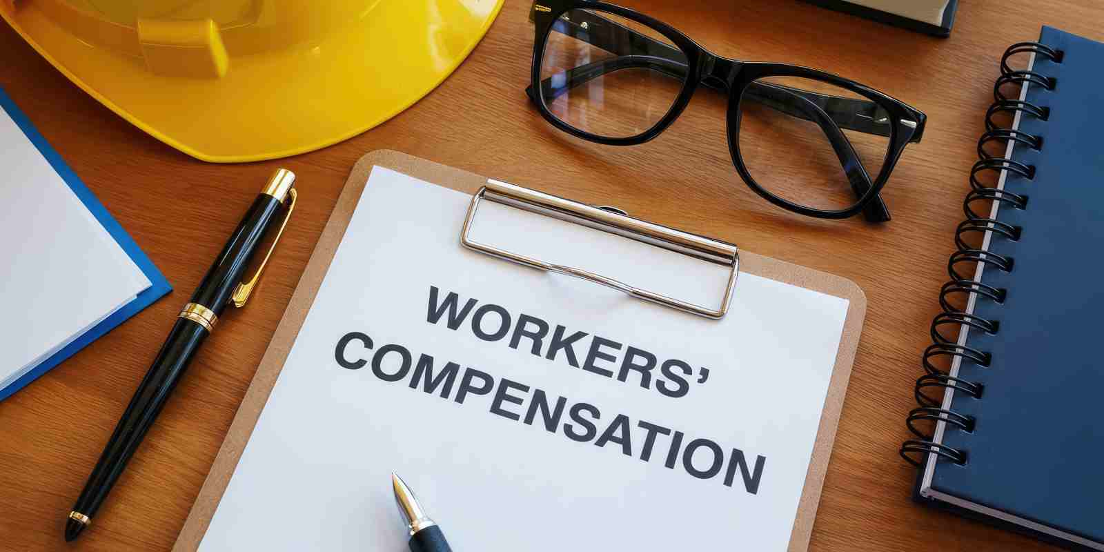 Workers Compensation Paper on Clipboard Near Pen Notebook and Specs
