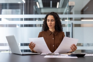 Businesswoman Reviewing Workers Compensation Insurance Documents at Her Desk