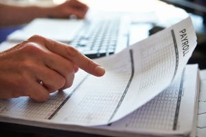 Person Reviewing Payroll Document During Audit at His Desk