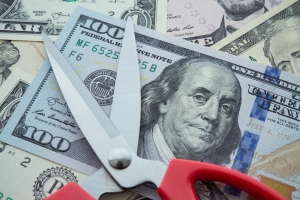 Scissors on US Dollar Representing Workers Compensation Insurance Costs Reduction