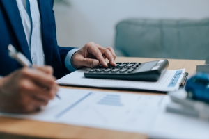 Businessman Using Calculator for Workers Compensation Insurance Cost