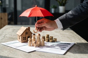 Homeowners Insurance Concept Represented by Miniature Wooden House and Red Umbrella