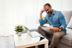Man Feeling Stressed While Reading Homeowners Insurance Denial Documents