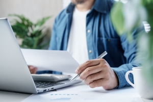 Manufacturing Business Owner Reviewing Workers Compensation Insurance Documents and Calculating Costs