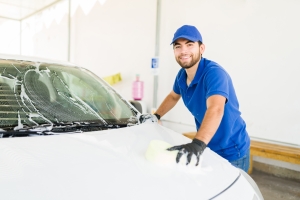 Smiling Car Wash Employee Cleaning a Car in Washing Center