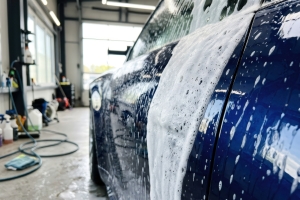 Blue Car Covered in Soap Foam During Deep Cleaning Process in Professional Garage