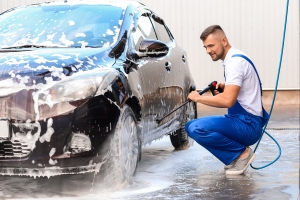 Male Worker Washing Car Outdoors with Pressure Washer