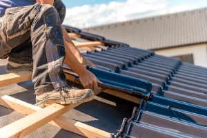 Worker Installing Ceramic Tile on a Wooden Frame of New Roof